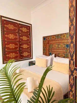 a bedroom with two beds and a plant at Dar Senhaji in Fès