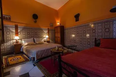 a bedroom with two beds and a table and lamps at Dar Tadla Fes in Fès