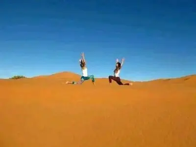 two people sitting on the sand in the desert at Merzouga activités in Merzouga