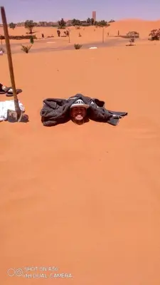 a man laying on the ground in the desert at Merzouga activités in Merzouga
