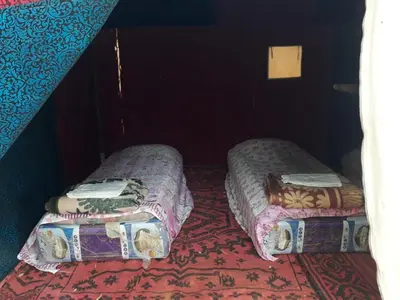 two twin beds in a room with a carpet at Merzouga activités in Merzouga