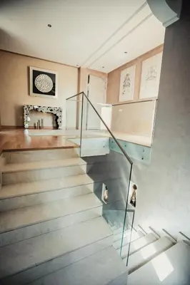 a staircase with glass railings in a house at Splendide Villa 5 chambres de luxe PRIVATISEE avec Cuisinière - Piscine chauffée - Jacuzzi & Hammam in Had Abdallah Rhiat