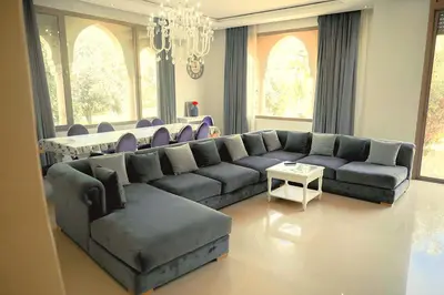 a living room with a couch and a table at Splendide Villa 5 chambres de luxe PRIVATISEE avec Cuisinière - Piscine chauffée - Jacuzzi & Hammam in Had Abdallah Rhiat
