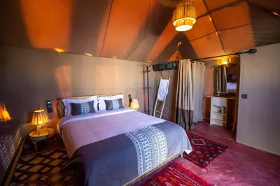 a bedroom with a large bed in a room at Morocco Tours Camp in Merzouga
