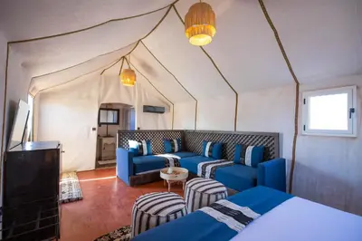 a room with blue couches and chairs in a tent at Morocco Tours Camp in Merzouga