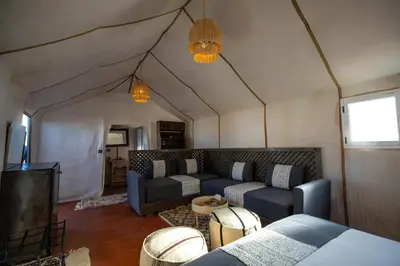a living room with a couch and a tv in a tent at Morocco Tours Camp in Merzouga