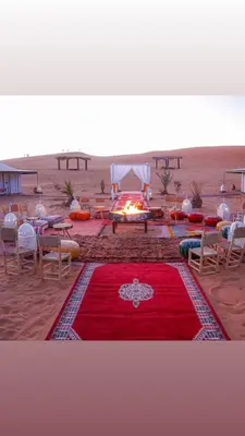 a red rug with a fire in the desert at Morocco Tours Camp in Merzouga