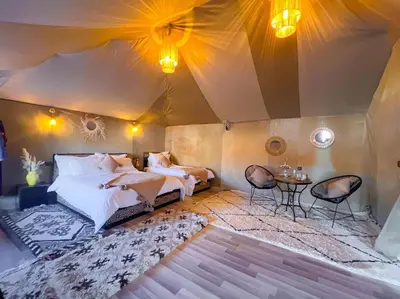 a bedroom with a tent with two beds and a table at Morocco Tours Camp in Merzouga