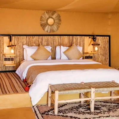 a bedroom with a large bed and a mirror at Kalimba Luxury Desert Camp in Merzouga