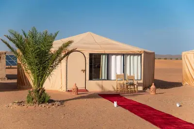 a tent in the middle of the desert with a red carpet at Kalimba Luxury Desert Camp in Merzouga