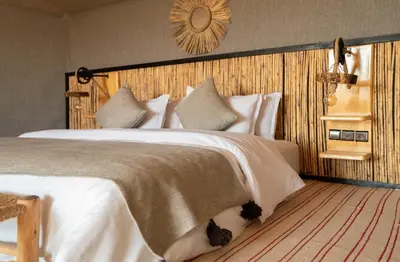 a bedroom with a large bed with white sheets at Kalimba Luxury Desert Camp in Merzouga