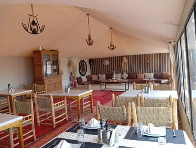 a dining room with tables and chairs in a tent at Kalimba Luxury Desert Camp in Merzouga