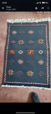 a person standing next to a blue rug with at Chez l'habitant Fatima in Arhbar