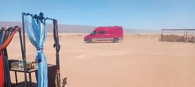 a red van is parked in the desert at Iriki Dreams in Bou Rbia