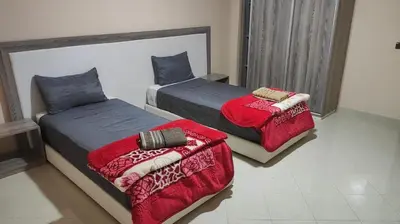 a bedroom with two beds with red sheets and avertisement at hotel DIJON ouzoud in Ouzoud