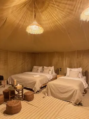 a bedroom with two beds and a chandelier at Desert Camp in Merzouga