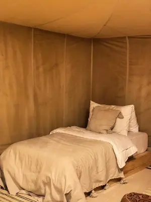 a bed in a room with a wall at Desert Camp in Merzouga
