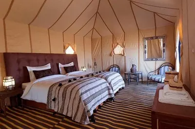 a bedroom with two beds in a tent at Amidinine Desert Camp in Merzouga