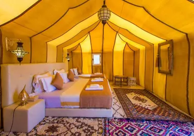 a bedroom with a bed in a tent at Amidinine Desert Camp in Merzouga