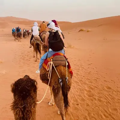a group of people riding horses in the desert at Amidinine Desert Camp in Merzouga