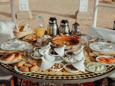 a table with plates of food on top of it at Amidinine Desert Camp in Merzouga