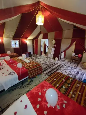 a large room with two beds and a chandelier at Amidinine Desert Camp in Merzouga
