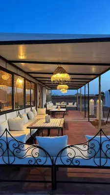 a patio with tables and chairs and a chandelier at Amidinine Desert Camp in Merzouga