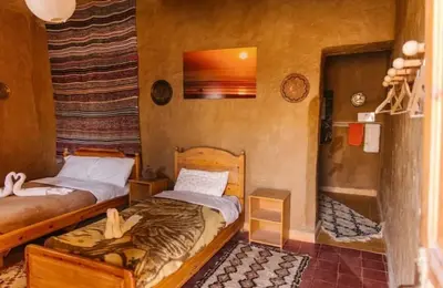 a bedroom with two beds in a room at Auberge Itrane merzouga in Merzane