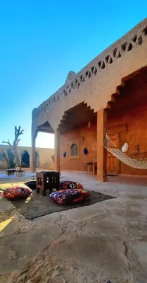 a large building with a hammock in front of it at Auberge Itrane merzouga in Merzane