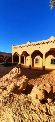 a house in the desert with a rock in front of it at Auberge Itrane merzouga in Merzane