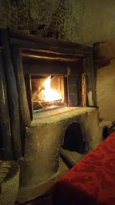 a stone fireplace with a fire in it at Auberge Itrane merzouga in Merzane