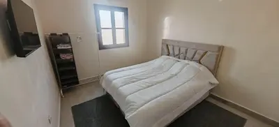 a bed in a room with a window at Appartement familial confortable au centre ville in El Kelaa des Srarhna