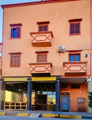 an orange building with windows and a storefront at Appartement familial confortable au centre ville in El Kelaa des Srarhna