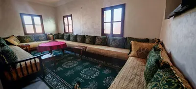 a living room with a long couch and a table at Appartement familial confortable au centre ville in El Kelaa des Srarhna