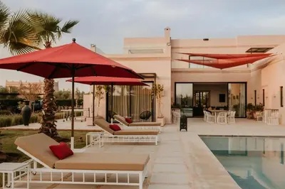 a villa with a swimming pool and red umbrellas at Luxury 5-Suite Villa with Heated Pool, Steam Room & Games in Marrakech