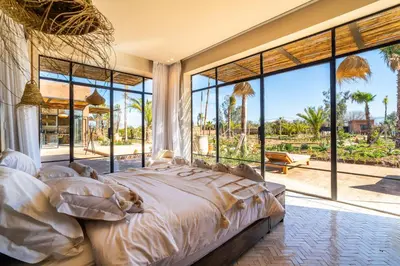 a bedroom with a large bed and large windows at VILLA 2s in Marrakech