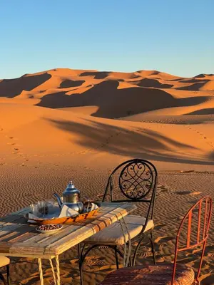 a wooden table and chairs in the desert at Moroccan Desert Camp in Merzouga