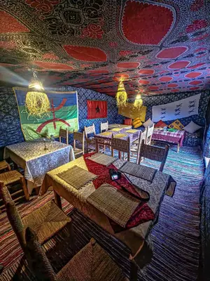 a dining room with tables and chairs and a colorful ceiling at Moroccan Desert Camp in Merzouga