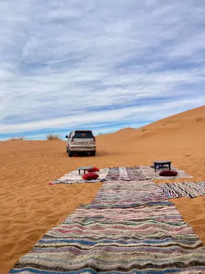 a car in the desert with a blanket in the sand at Moroccan Desert Camp in Merzouga