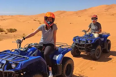 two people riding on atvs in the desert at Moroccan Desert Camp in Merzouga