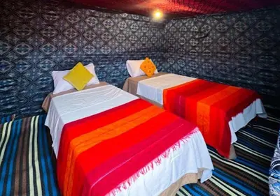 two beds in a room with colorful blankets at Moroccan Desert Camp in Merzouga