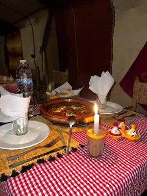 a table with a pizza and a candle on it at Moroccan Desert Camp in Merzouga