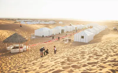 a group of people walking in the desert at Amodo desert camp in Merzouga
