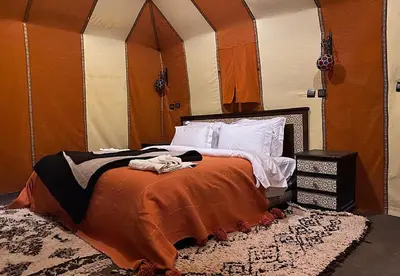 a bedroom with a bed with an orange blanket at Amodo desert camp in Merzouga