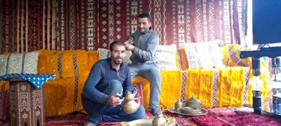 two men sitting on a couch cutting another mans hair at Hôtel flora in Beni Mellal