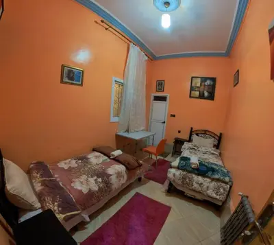two beds in a room with orange walls at Maison d'hôtes de Zaida in Zaida