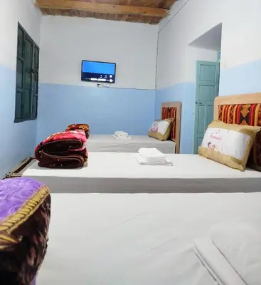 two beds in a room with a tv on the wall at Tagmat guest house in Toufrine