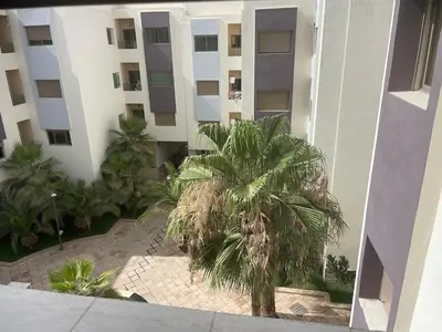 a palm tree in front of a building at Chic and comfortable air-conditioned apartment in Fès