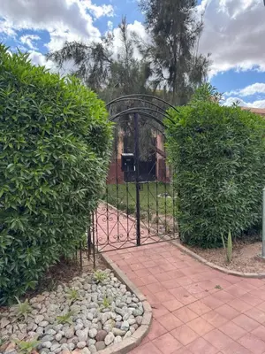a black gate in a garden with bushes at Beautiful Villa near Marrakesh in Marrakech