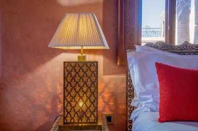 a lamp sitting on a table next to a bed at Atlas Castle Marrakech in Marrakech